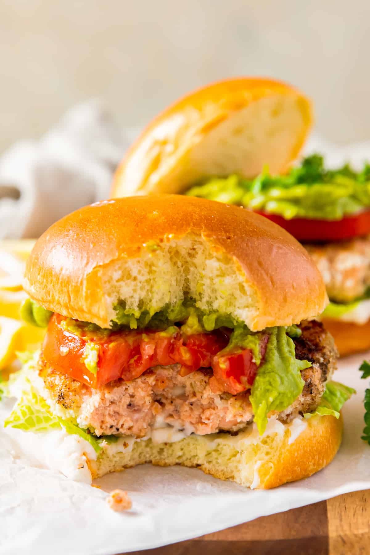 salmon burger on a bun with lettuce and tomato with a bite taken from it