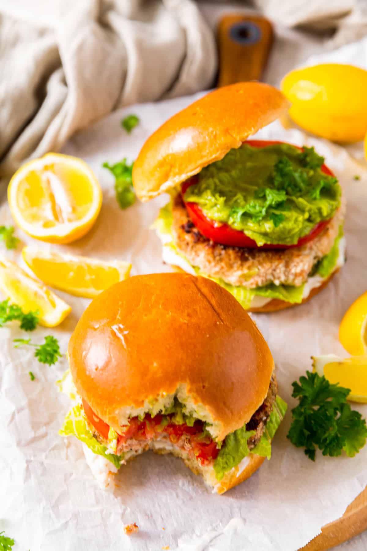 salmon burgers on buns with a bite taken from one