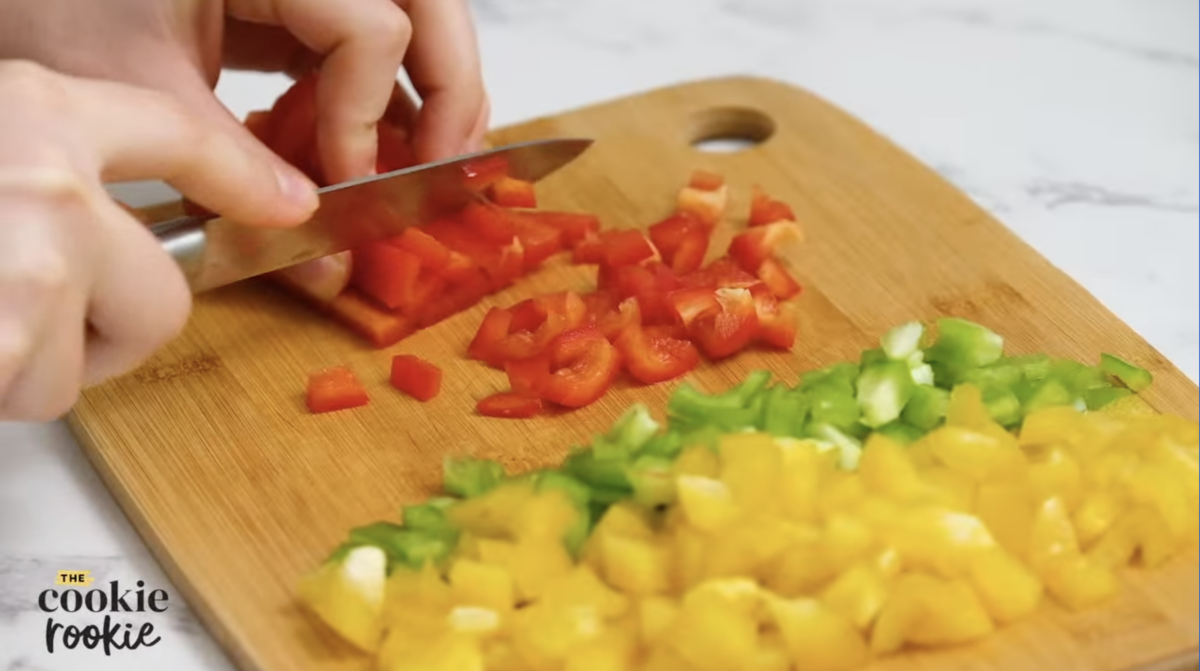 a person cutting bell peppers into chunks with a knife.
