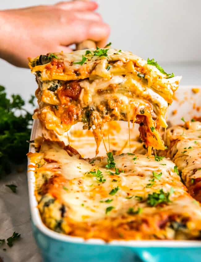 hand removing a slice of vegetarian lasagna from the baking dish with a spatula