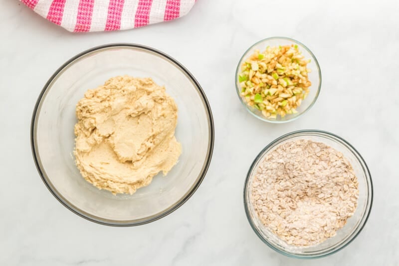 wet ingredients in a glass bowl, dry ingredients in a glass bowl, and diced apple in a glass bowl