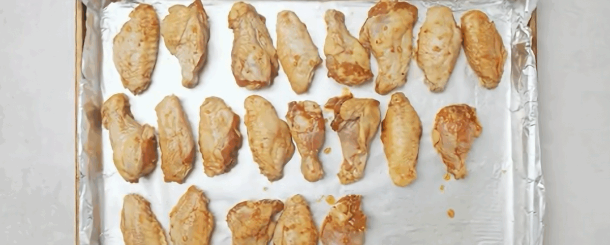 Placing the wings on an aluminum lined baking sheet. 