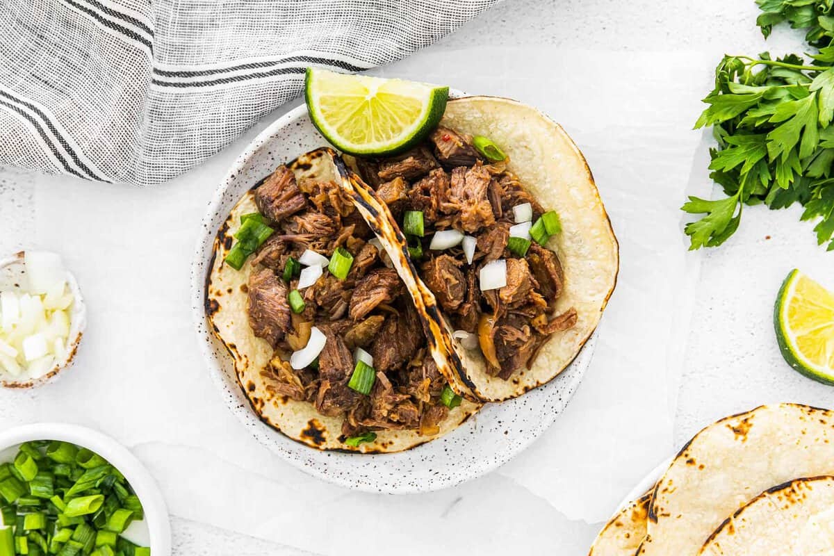 crockpot beef carnitas served on a plate with a lime garnish