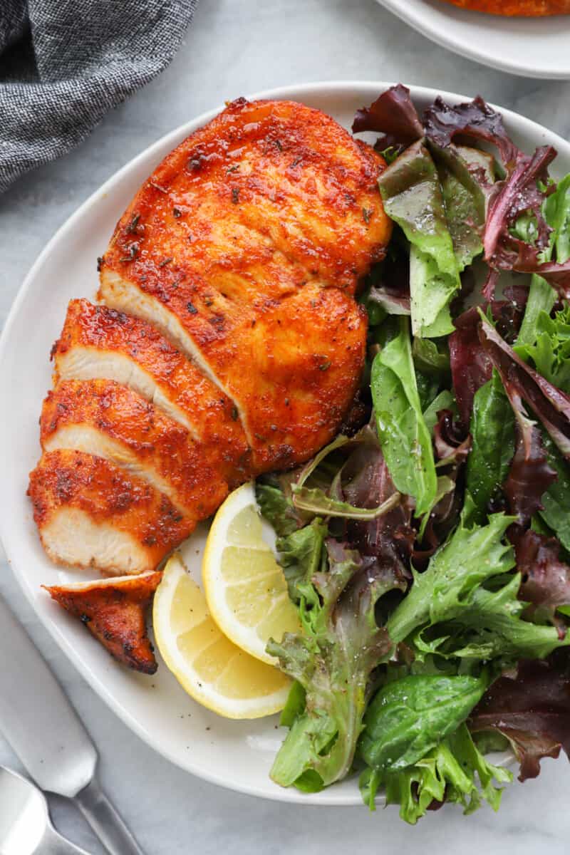 sliced chicken breast on a white plate with salad