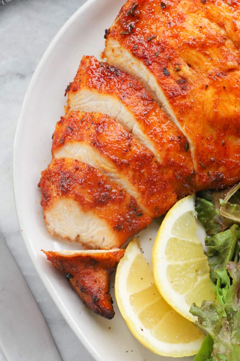 sliced chicken breast on a white plate with salad