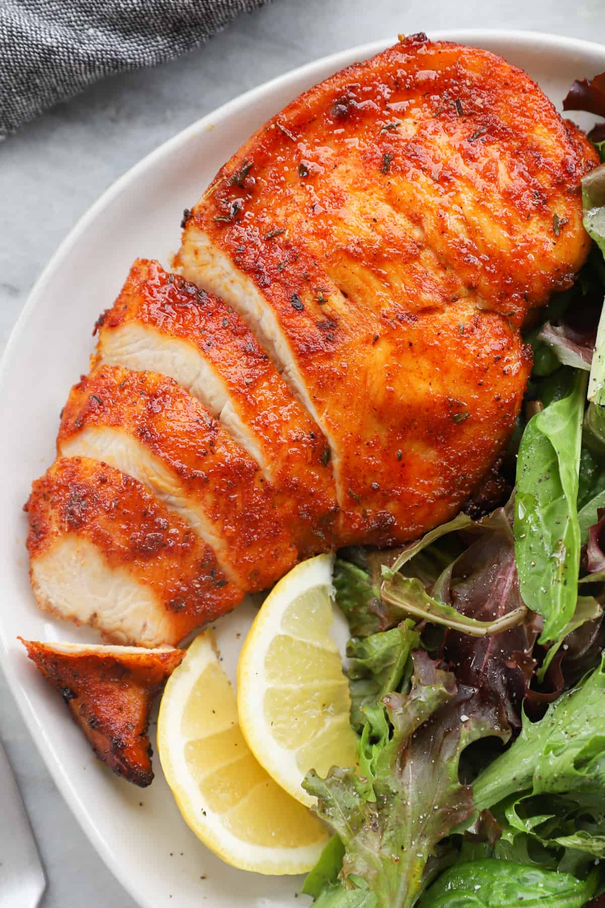 sliced chicken breast on a white plate with salad