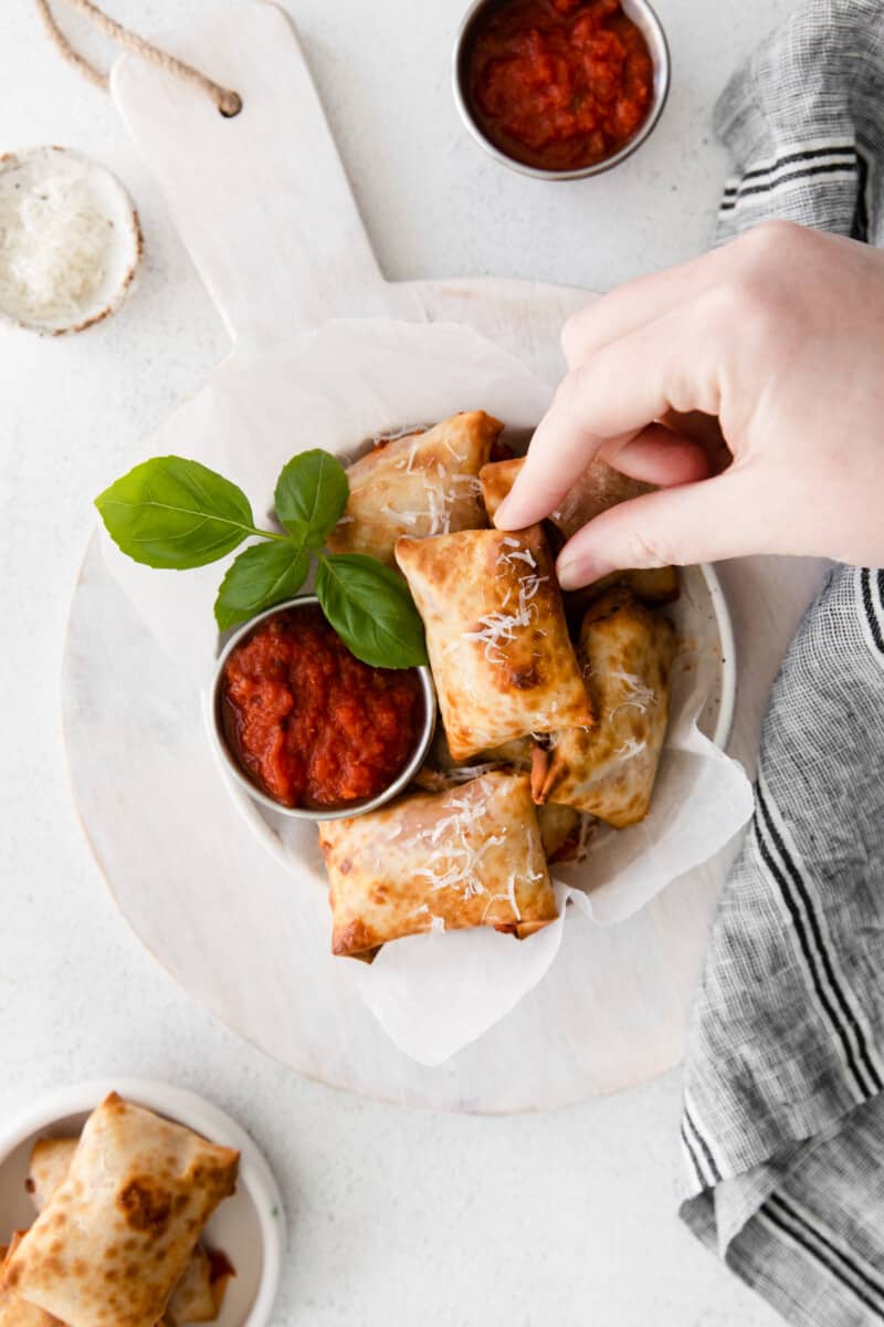 hand grabbing a pizza roll out of a bowl