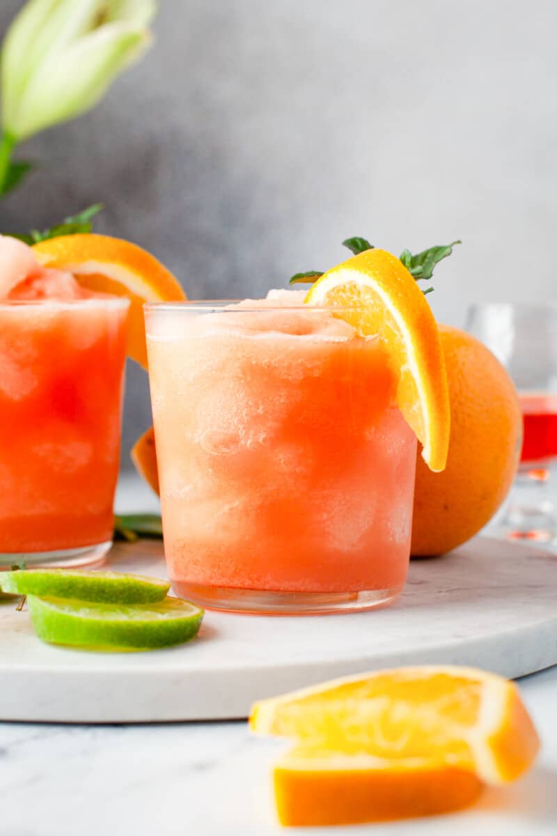 frozen Aperol margaritas in glasses with orange slice and mint garnishes