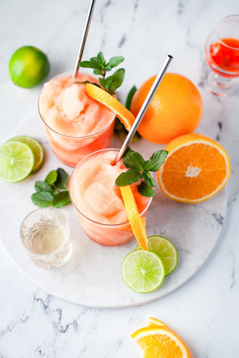 frozen Aperol margaritas in glasses with orange slice and mint garnishes