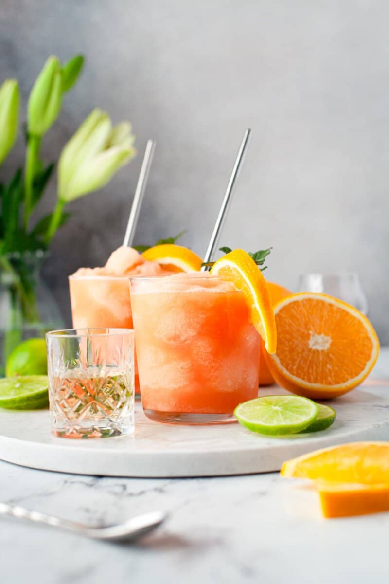 frozen Aperol margaritas in glasses with orange slice and mint garnishes