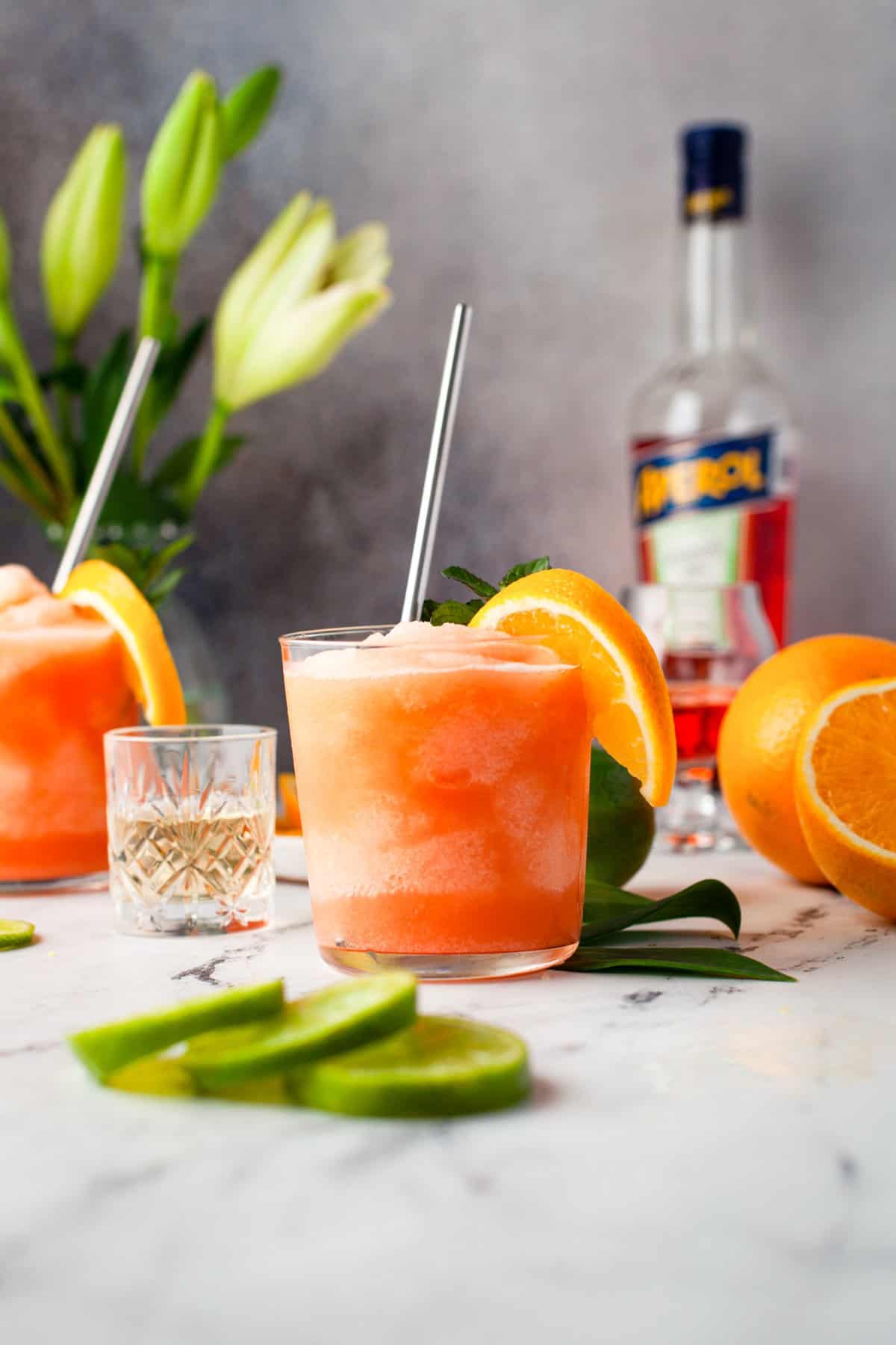 frozen Aperol margarita in a glass with orange slice and mint garnishes