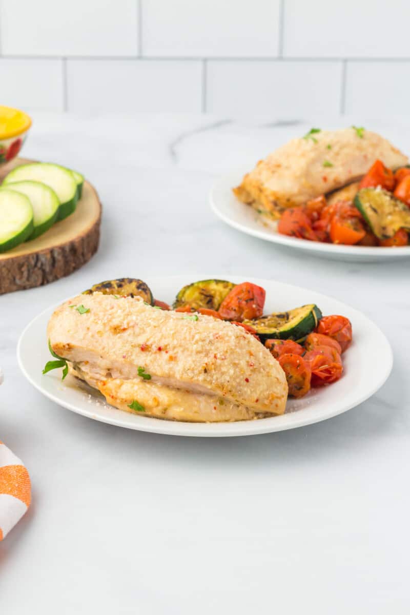 Italian chicken breast on a white plate with roasted vegetables