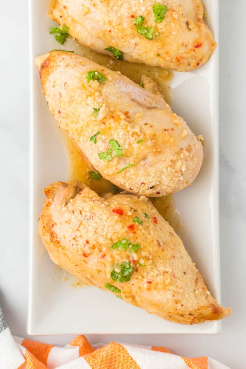 overhead image of 3 baked Italian chicken breasts on a white serving platter