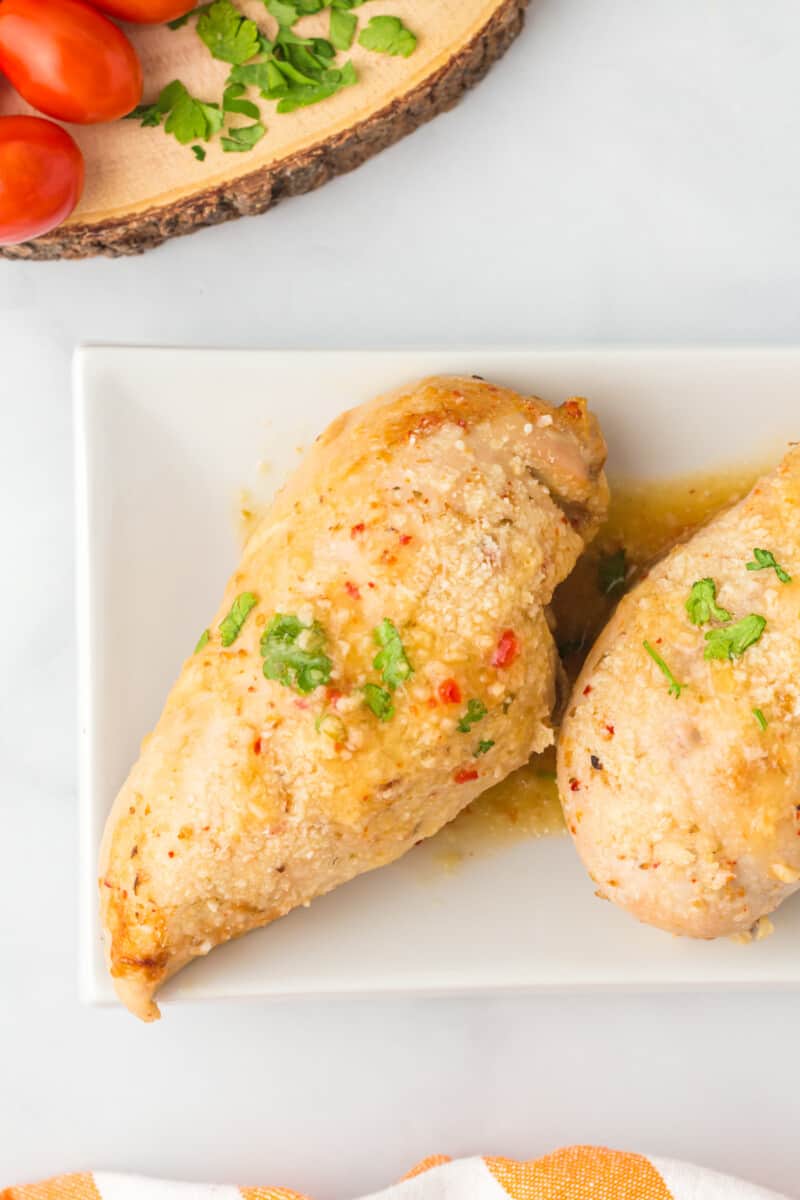 2 baked Italian chicken breasts on a white serving platter