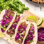 barbacoa tacos on a wood serving board