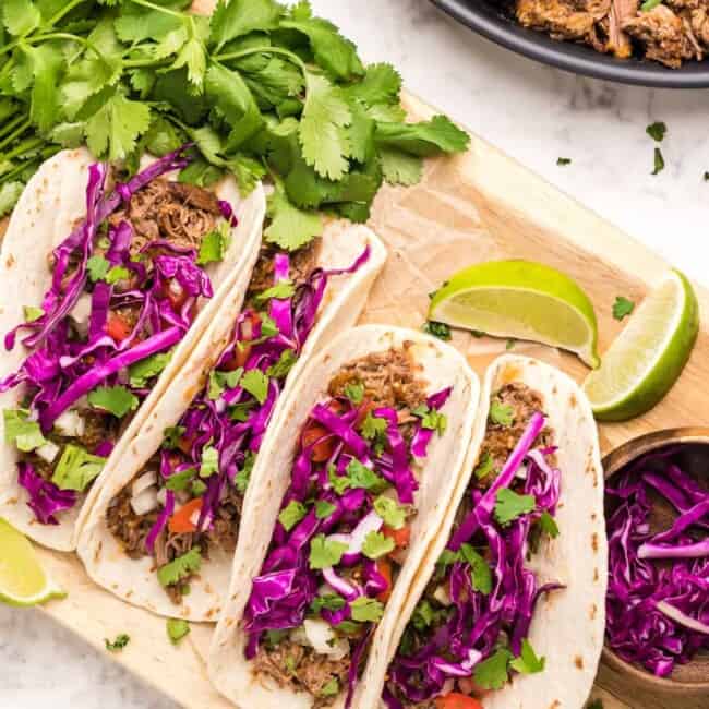 barbacoa tacos on a wood serving board