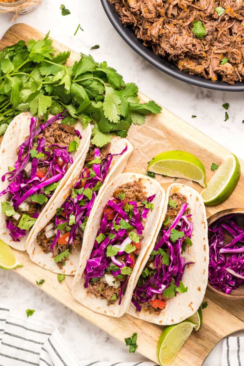 barbacoa tacos on a wood serving board