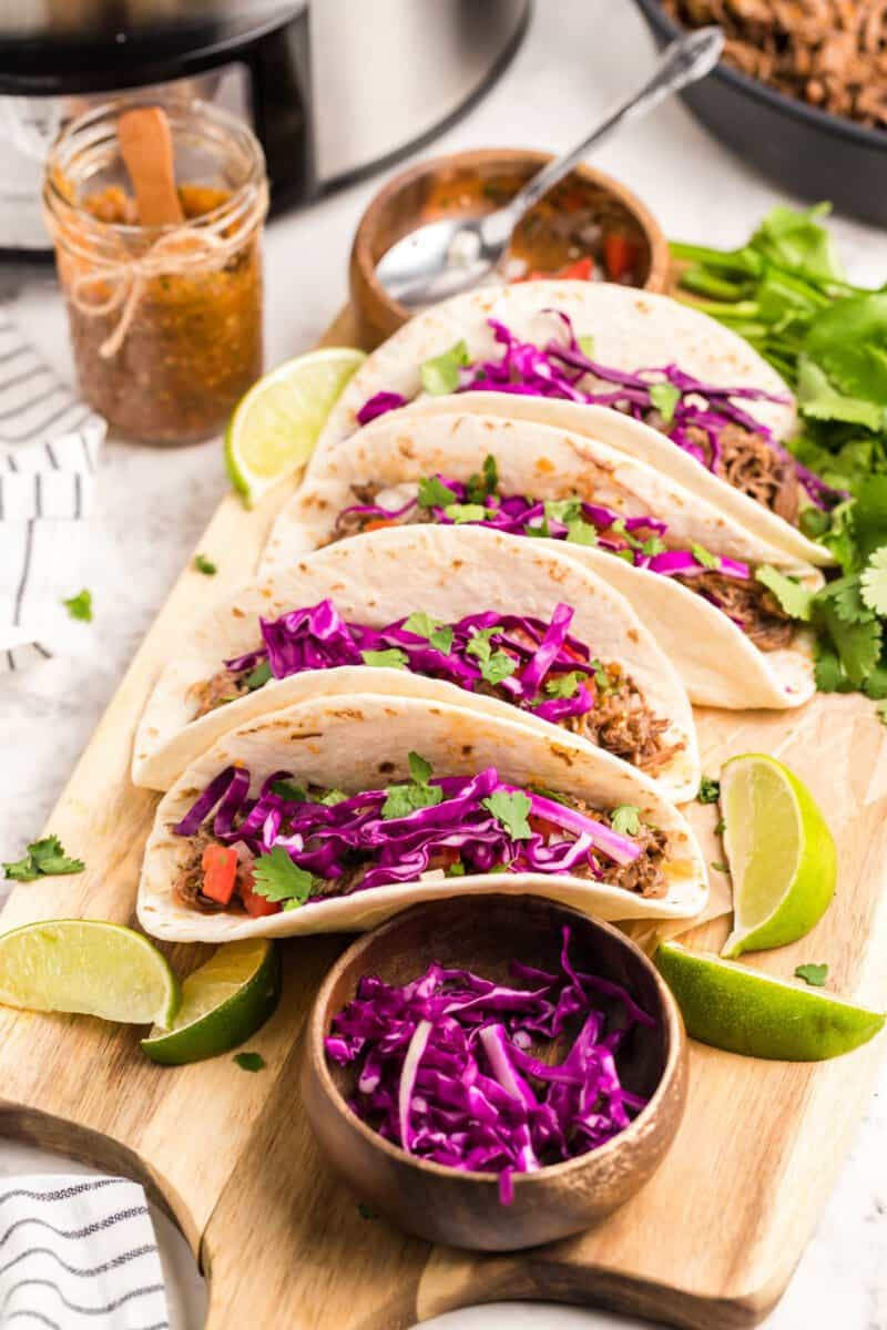 barbacoa tacos on a wood serving board