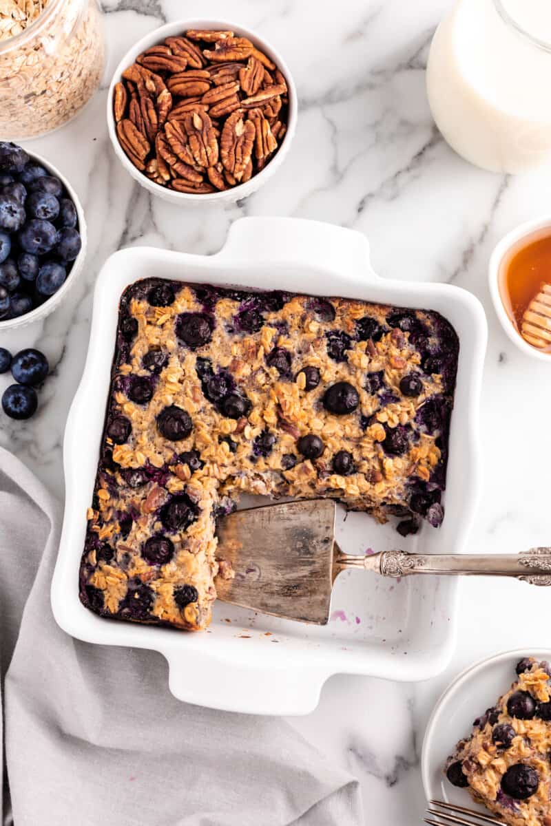 blueberry baked oatmeal in a white baking dish with a slice removed