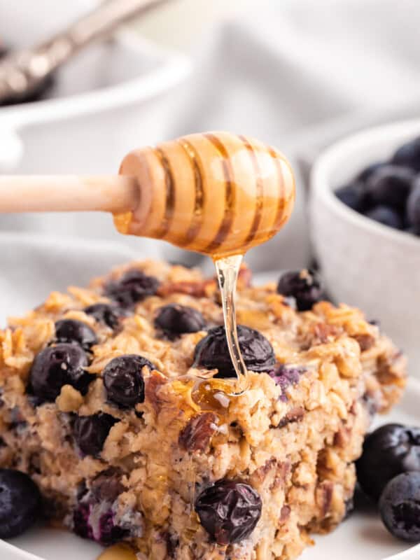drizzling honey onto a piece of blueberry baked oatmeal on a white plate - 132