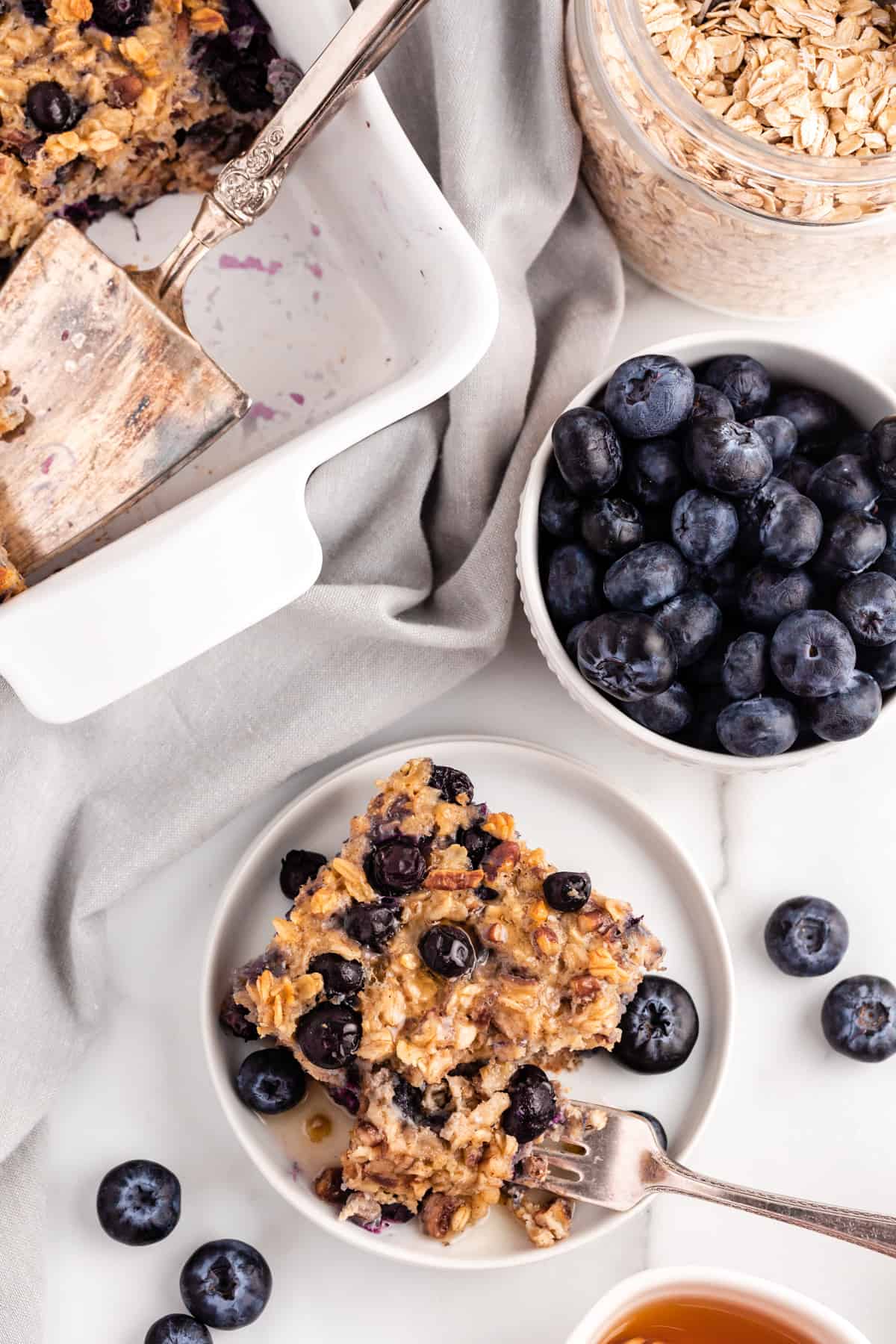 Slice of blueberry baked oatmeal on a white plate with a fork. - 12