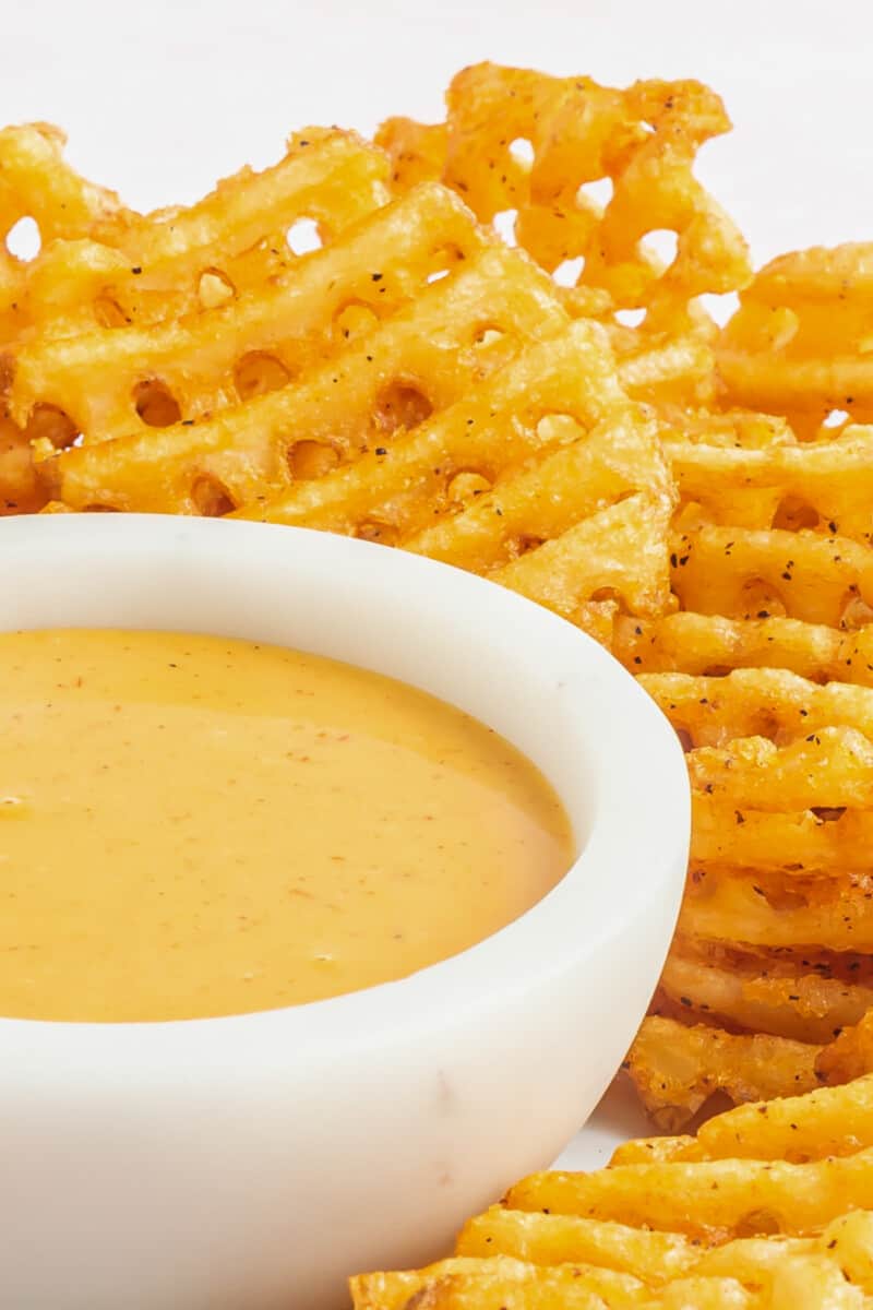 chick-fil-a sauce in a white bowl on a serving platter with waffle fries