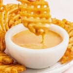 hand dipping a waffle fry into a bowl of chick-fil-a sauce