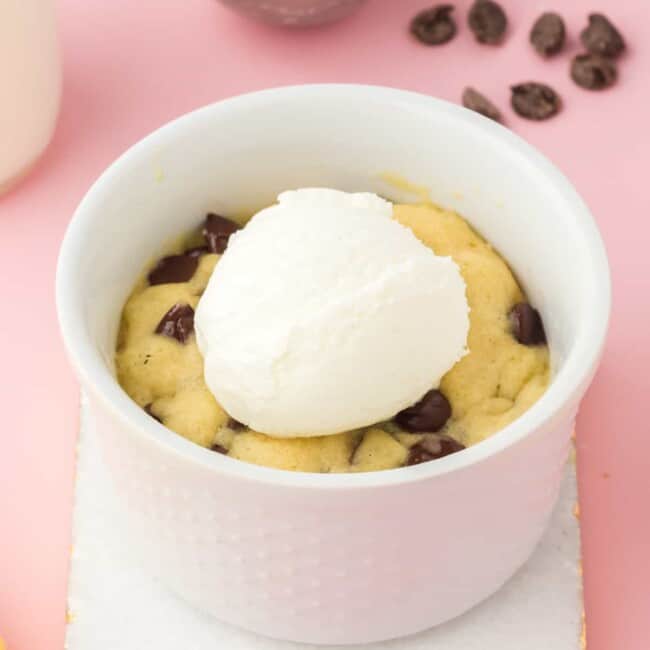 chocolate chip cookie in a mug topped with a scoop of vanilla ice cream