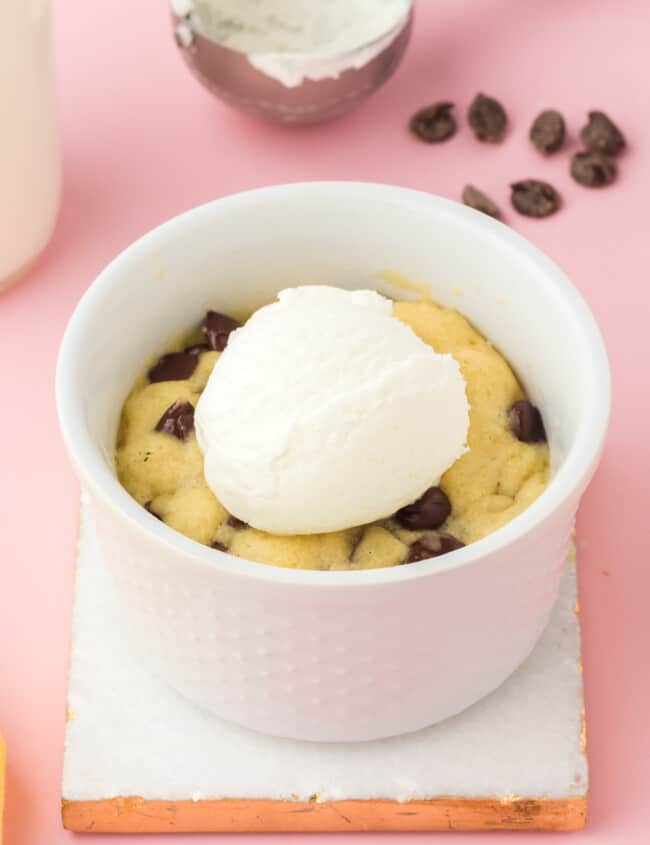 chocolate chip cookie in a mug topped with a scoop of vanilla ice cream