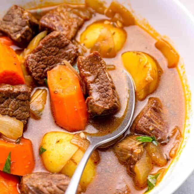 beef stew in a white bowl with a spoon