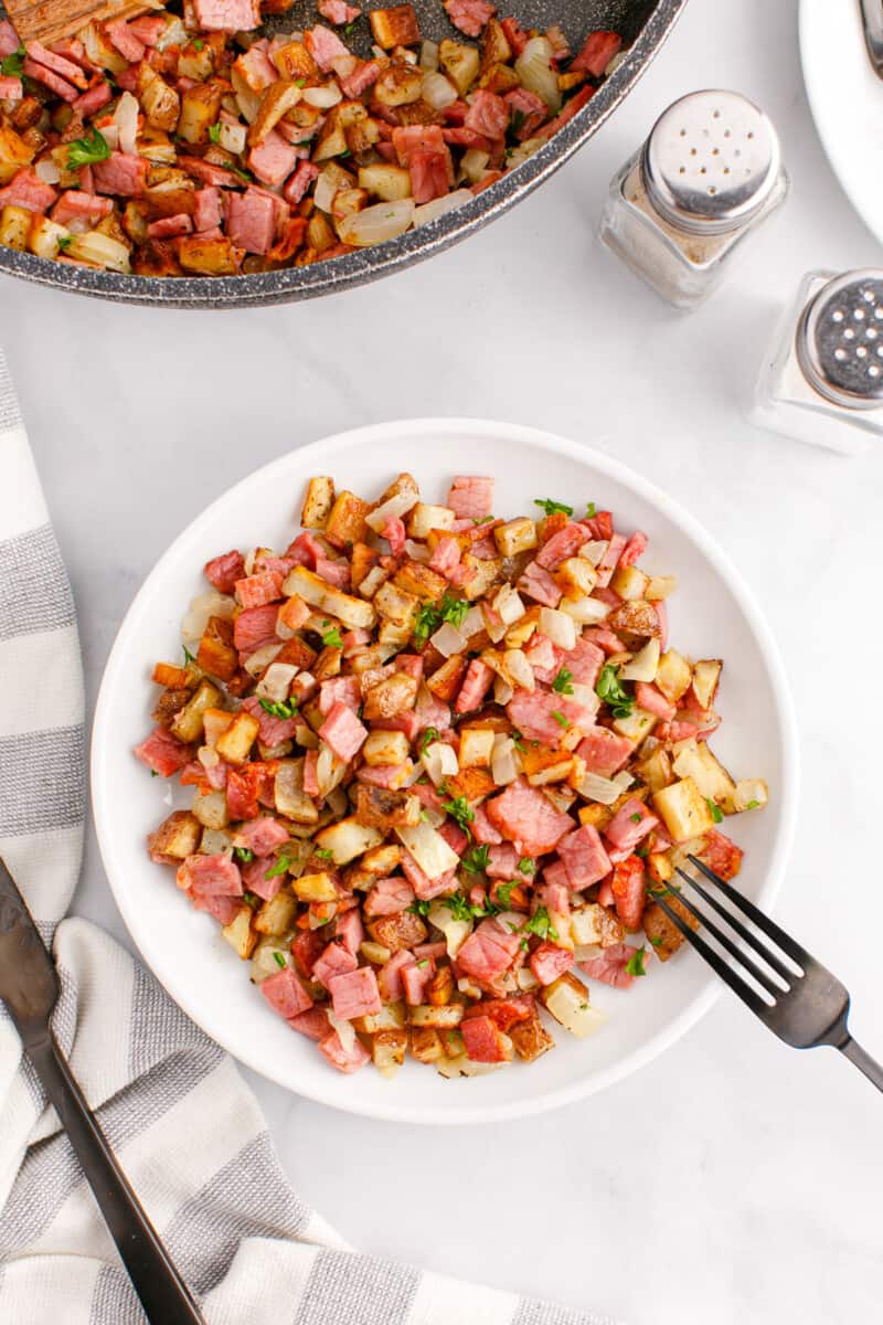 serving of corned beef hash on a white plate with a fork