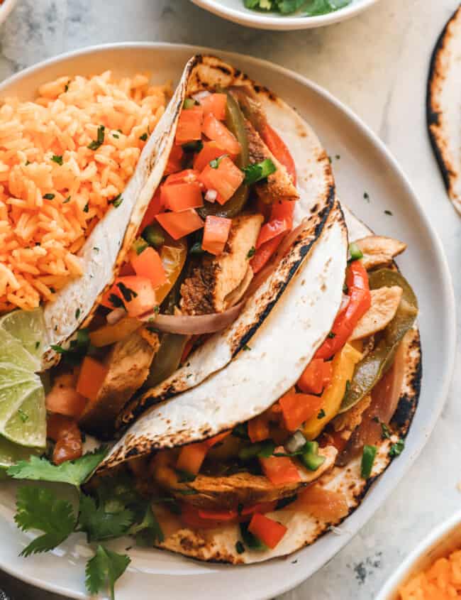 chicken fajitas on a white plate with rice