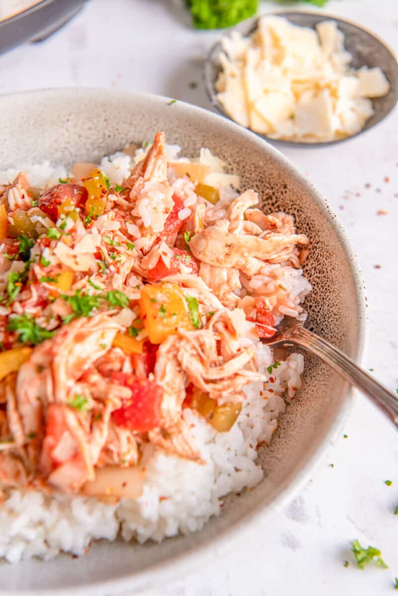 shredded italian chicken on top of rice in a bowl with a fork