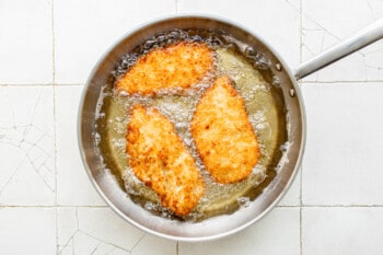 3 chicken breasts frying in a skillet