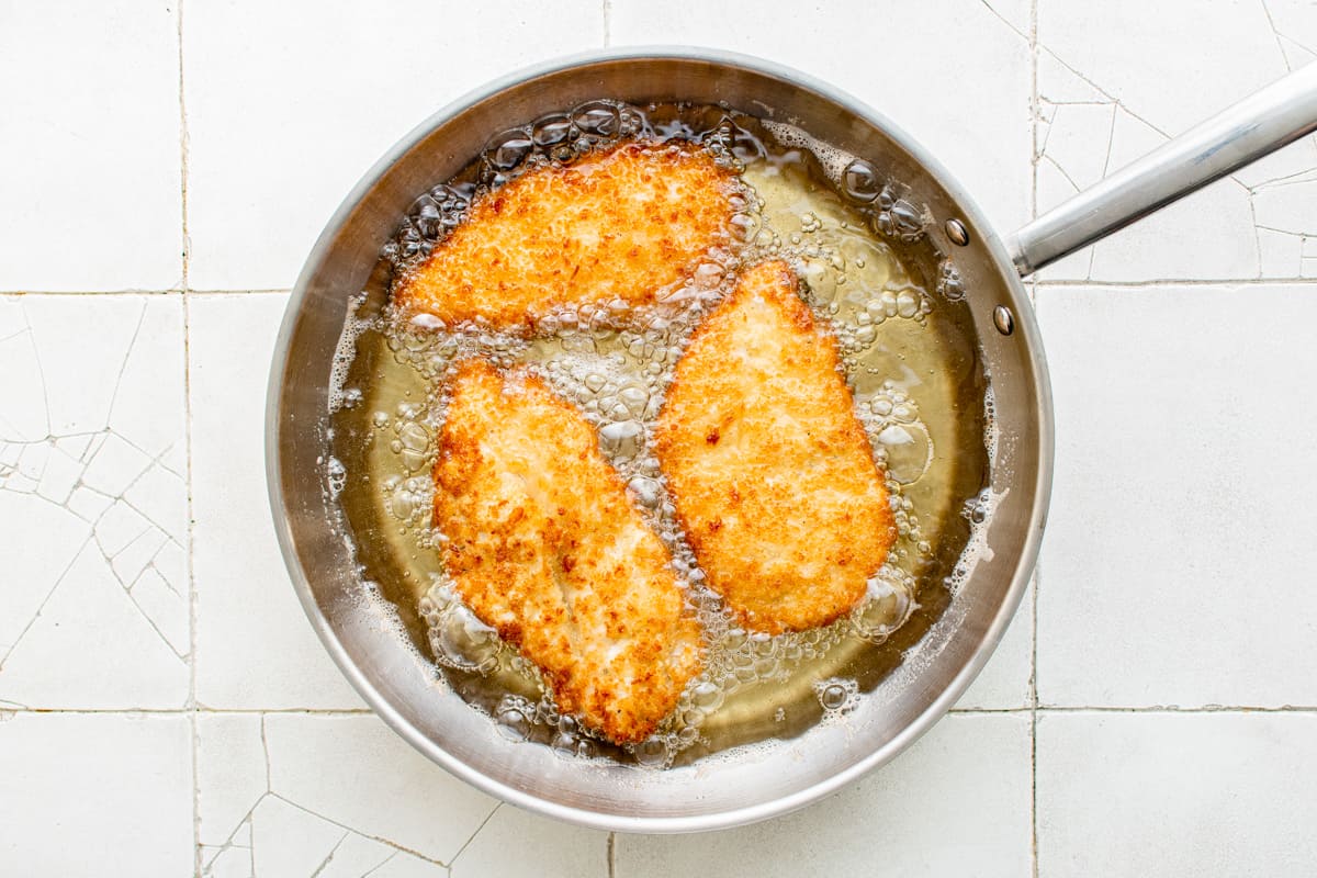 3 chicken breasts frying in a skillet