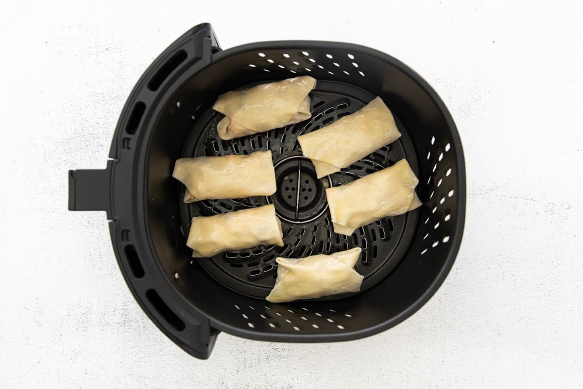 6 egg rolls in an air fryer before cooking.