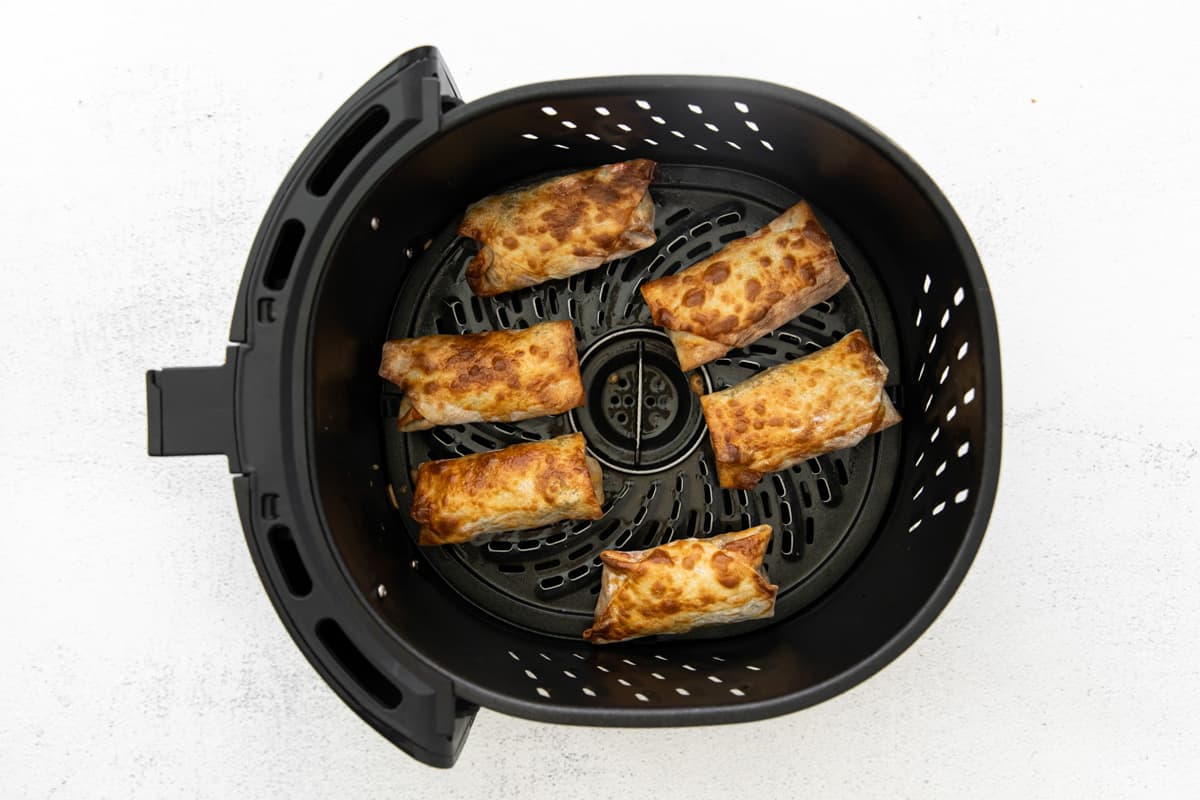 6 cooked egg rolls in an air fryer.