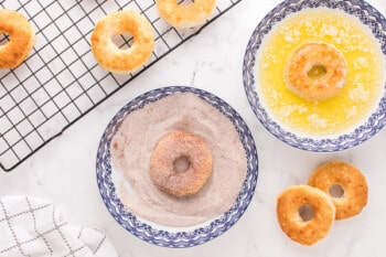 air fryer donuts in a bowl of melted butter and a bowl of cinnamon sugar mixture