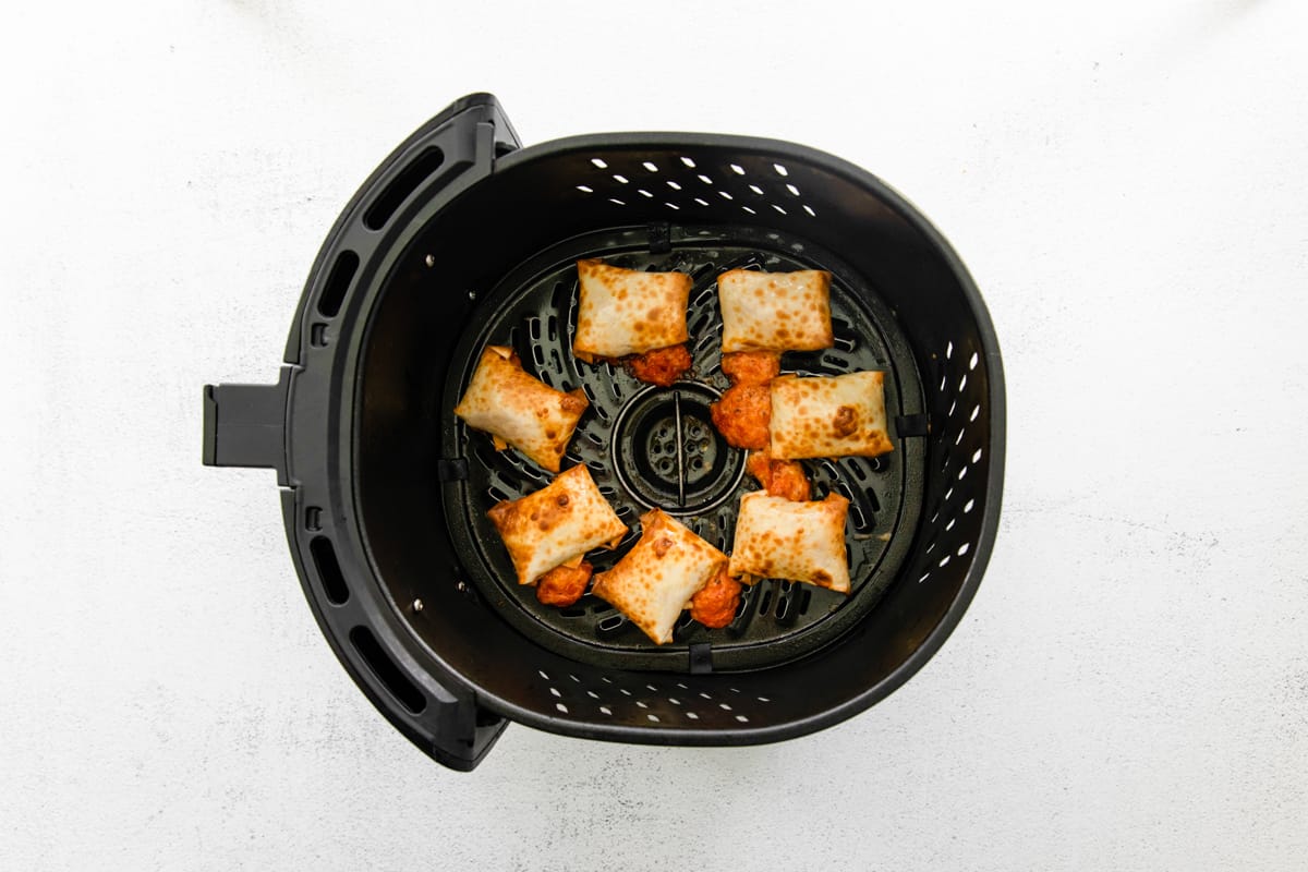 Pizza rolls in an air fryer after cooking.