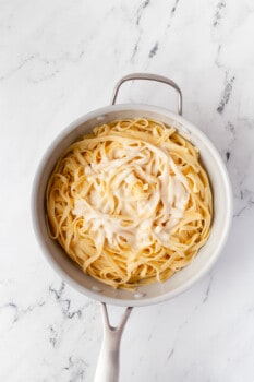 Alfredo sauce on top of fettuccine noodles in a saucepan