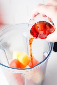 hand pouring Aperol into a blender