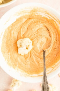 cauliflower floret in a bowl of buffalo batter