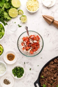 pico de gallo in a glass bowl with a spoon