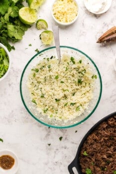 cilantro lime cauliflower rice in a glass bowl with a spoon