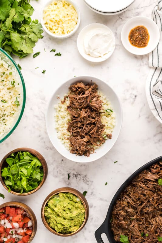 cauliflower rice in a bowl topped with barbacoa meat