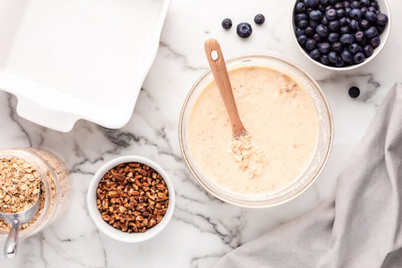 oatmeal mixture in a glass bowl with a wood spoon