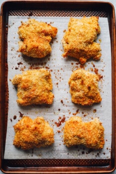 chicken thighs on a parchment paper lined baking sheet after baking