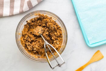 chocolate peanut butter protein balls mixture in a glass bowl with a cookie scoop