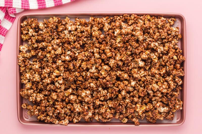 chocolate popcorn on a parchment paper lined baking sheet