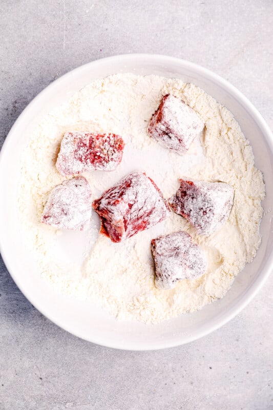 chunks of beef in a bowl of flour